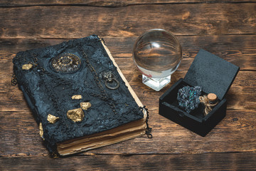 Book of magic and crystal ball on brown wooden table background.