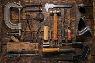 Old carpentry work tools on a brown wooden table background.