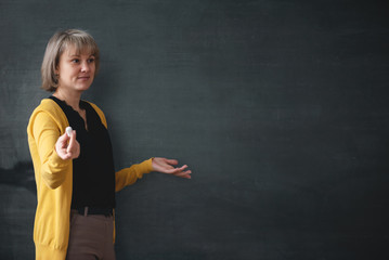 Teacher with a piece of chalk standing on a blackboard background with copy space. © Dmitriy