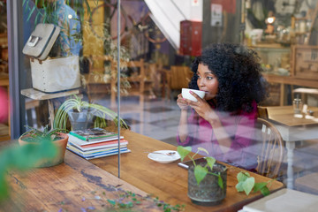 Pensive young African American woman drinking coffee in a cafe