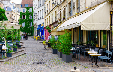 Cozy street with tables of cafe in Paris, France