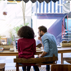 Diverse young couple using their laptop together in a cafe