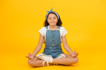 Relax and get comfortable. Small girl sit in yoga posture on yellow background. Little child enjoy yoga training. Yoga meditation. Meditation or yoga