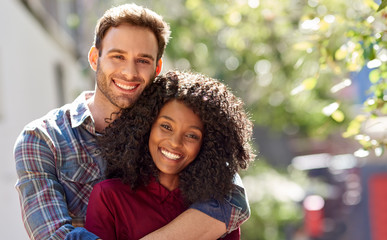 Diverse couple affectionately standing together ouside on a sunny day - Powered by Adobe