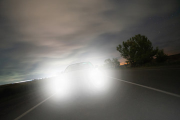 the car rushing along the night highway dazzles with the high beam its headlights