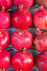 Red pomegranate - Punica granatum - fruits in rows on display for sale. This fruit is full of vitamins and is in season in autumn both in the Northern and Southern Hemispheres. Vertical photo.