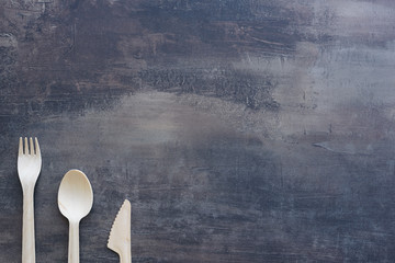 Top view of natural cutlery - wooden knife, spoon and fork with copy space. Marble black kitchen counter.