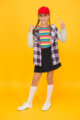 Hipster in pigtails. Happy little hipster wear baseball cap yellow background. Cute small hipster smile with fashionable look. Adorable child in hipster style