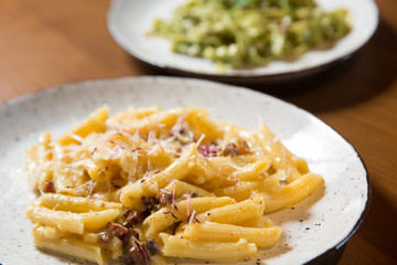 Penne pasta in cheese sauce with bacon on a wooden background