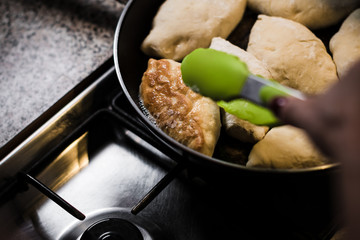 Fried pies in a pan standing on a gas stove