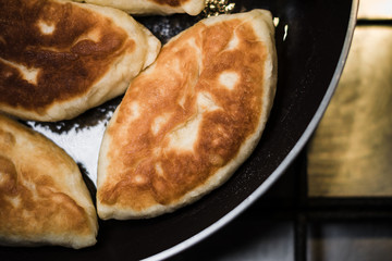 Fresh pies in a pan, which stands on a gas stove, top view