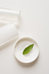 Means for skin care, rejuvenation and hydration of the face. Cream, micellar water and moisturizing lotion on a white background with a green leaf. The concept of self-care and care for the skin