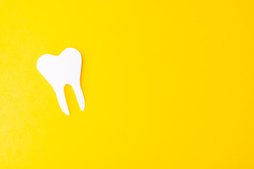 Paper tooth on a yellow background. Place for text. From above
