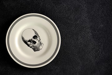 Plate with a pattern of a skull, fork and knife. Background for Halloween. Top view. Copy space. 