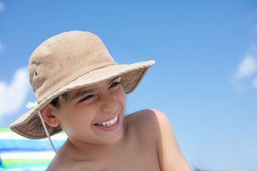 Boy smiling looking downward and wearing a hat