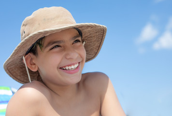 Boy smiling looking upward and wearing a hat