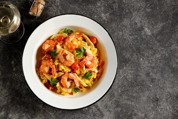 Paella or risotto with chicken breast, shrimp tails, carrots, onions, cherry tomatoes, white wine and chicken stock. Top view. 