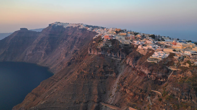 Aerial drone photo of Fira main village of Santorini island with breathtaking views to Caldera and Aegean sea at sunset with beautiful golden colours, Cyclades, Greece