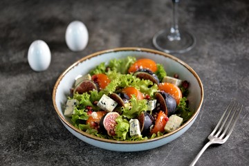 Healthy salad of persimmons, figs, blue cheese, pomegranate seeds, parmesan, lettuce and olive oil.