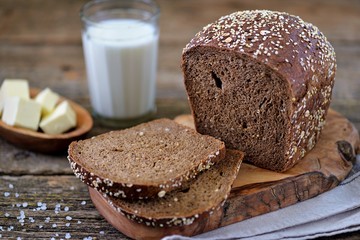 Healthy rye bread with organic milk and butter on an old wooden background.