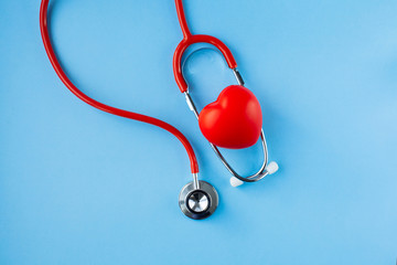 Stethoscope and red heart on blue background.