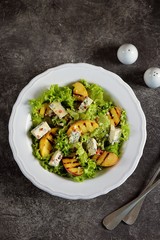 Grilled peach salad with lettuce, blue cheese, parmesan, olive oil and pink pepper.
