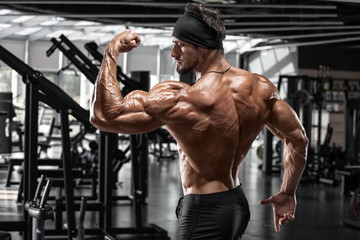 Muscular man showing biceps and back muscles. Strong male naked torso - obrazy, fototapety, plakaty
