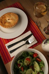 Canadian cuisine, meat pie on table as main course, mixed salad bowl and white wine
