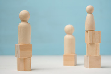 Three abstract wooden figures of people stand on different levels.
