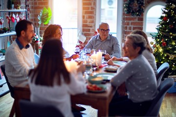 Family and friends dining at home celebrating christmas eve with traditional food and decoration, all sitting on the table together