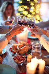 Family and friends dining at home celebrating christmas eve with traditional food and decoration, all sitting on the table together