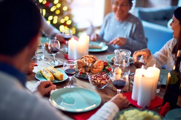 Family and friends dining at home celebrating christmas eve with traditional food and decoration, all sitting on the table together
