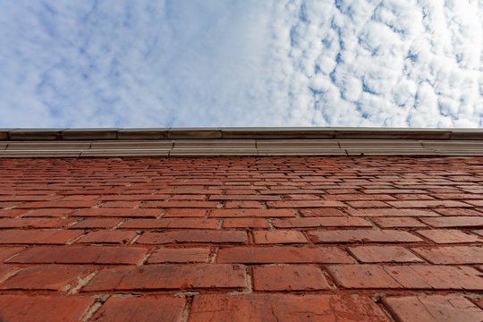 Background image - red brick wall on a background of blue sky in white clouds