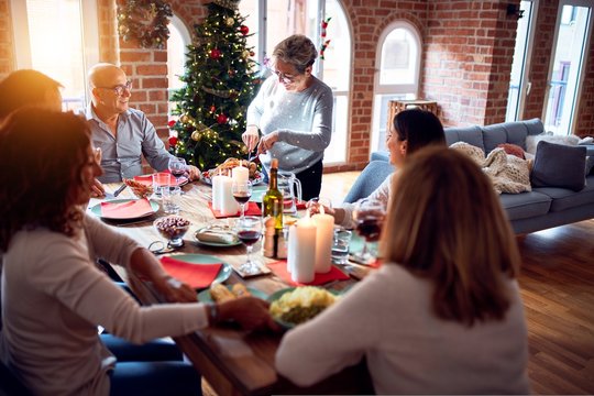 Family And Friends Dining At Home Celebrating Christmas Eve With Traditional Food And Decoration, Preparing Turkey For Dinner