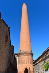 Tall old brick industrial chimney in south of France attached to a liquor factory. Industrial brick chimney stacks were once a very common sight around Europe. 