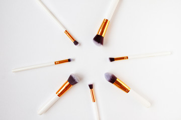 Flat lay top view of female cosmetics brushes set for makeup in the middle on white background. Cosmetics and beauty concept...............................................
