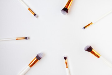 Flat lay top view of female cosmetics brushes set for makeup on white background. Cosmetics and beauty concept with space for text in the middle.
