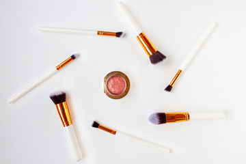 Flat lay top view of female cosmetics brushes set for makeup and closed rouge in the middle on white background. Cosmetics and beauty concept. Make up concept with space for text..........