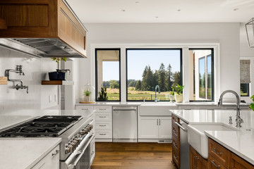 Kitchen detail in new luxury home, with gas range, two farmhouse sinks, quartz countertops, and...