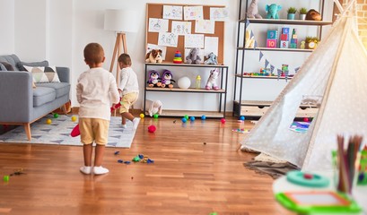 Adorable blonde twins playing around lots of toys at kindergarten