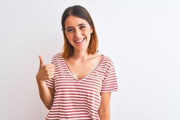 Beautiful redhead woman wearing casual striped red t-shirt over isolated background doing happy thumbs up gesture with hand. Approving expression looking at the camera showing success.