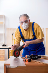 Old male carpenter working in workshop
