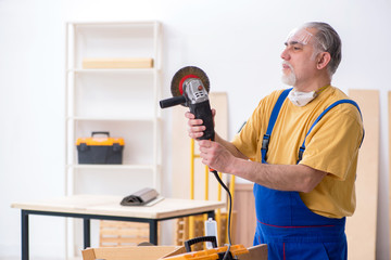 Old male carpenter working in workshop