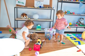 Adorable toddlers playing around lots of toys at kindergarten