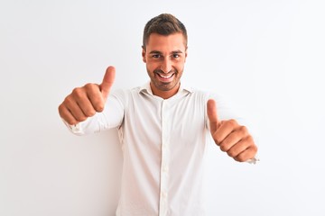 Young handsome business man wearing elegant shirt over isolated background approving doing positive gesture with hand, thumbs up smiling and happy for success. Winner gesture.