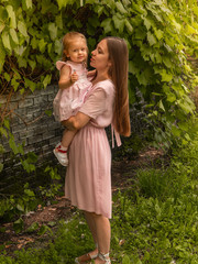 Mom and daughter walk and play in the park. Dressed in dresses. Sunny day, weekend in a city park.