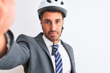 Young handsome business man wearing bike helmet taking a selfie over isolated background with a confident expression on smart face thinking serious