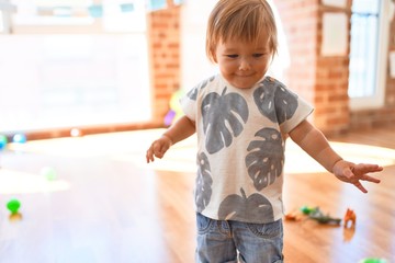 Adorable toddler playing around lots of toys at kindergarten