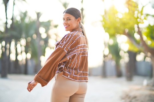 Young beautiful woman wearing jacket smiling happy and confident. Standing with smile on face at the town park