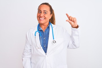 Middle age mature doctor woman wearing stethoscope over isolated background smiling and confident gesturing with hand doing small size sign with fingers looking and the camera. Measure concept.